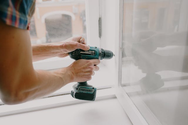 a%20contractor%20using%20a%20drill%20to%20fix%20a%20window%20hinge